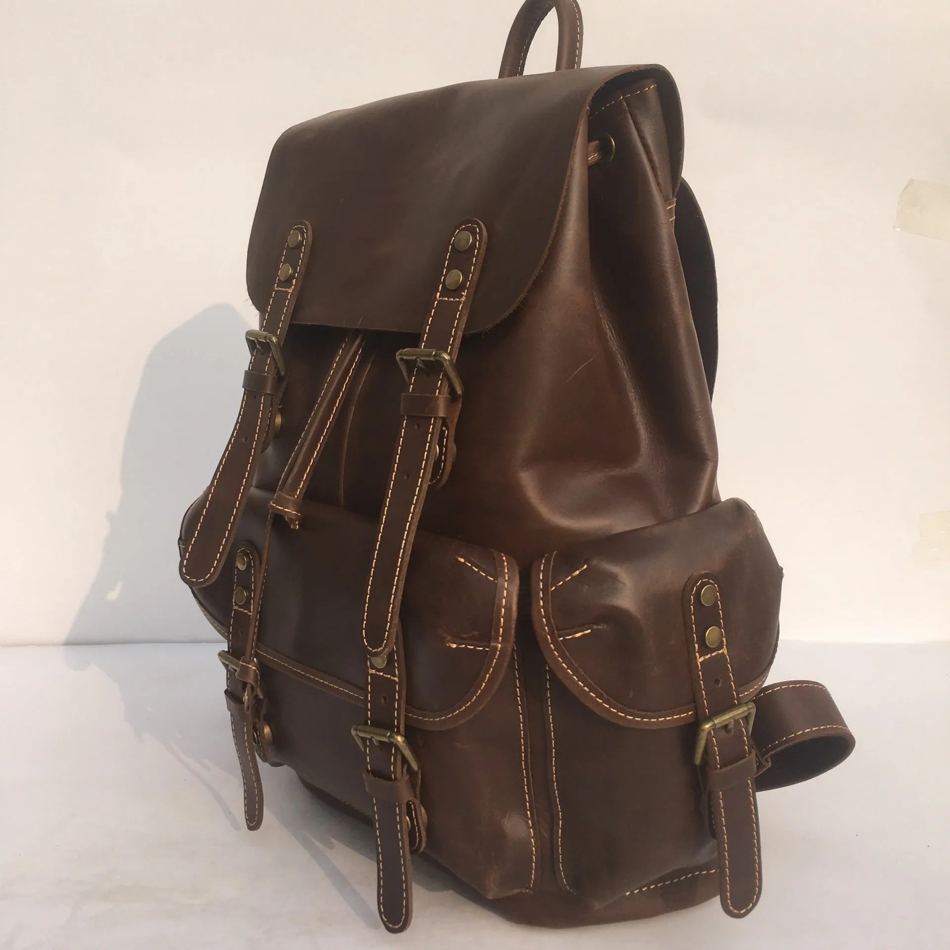 Brown men's leather backpack with an air pillow belt on the straps.