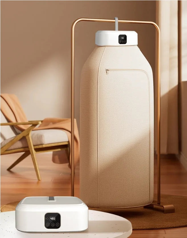 White cylindrical foldable clothes drier with remote control on a table.