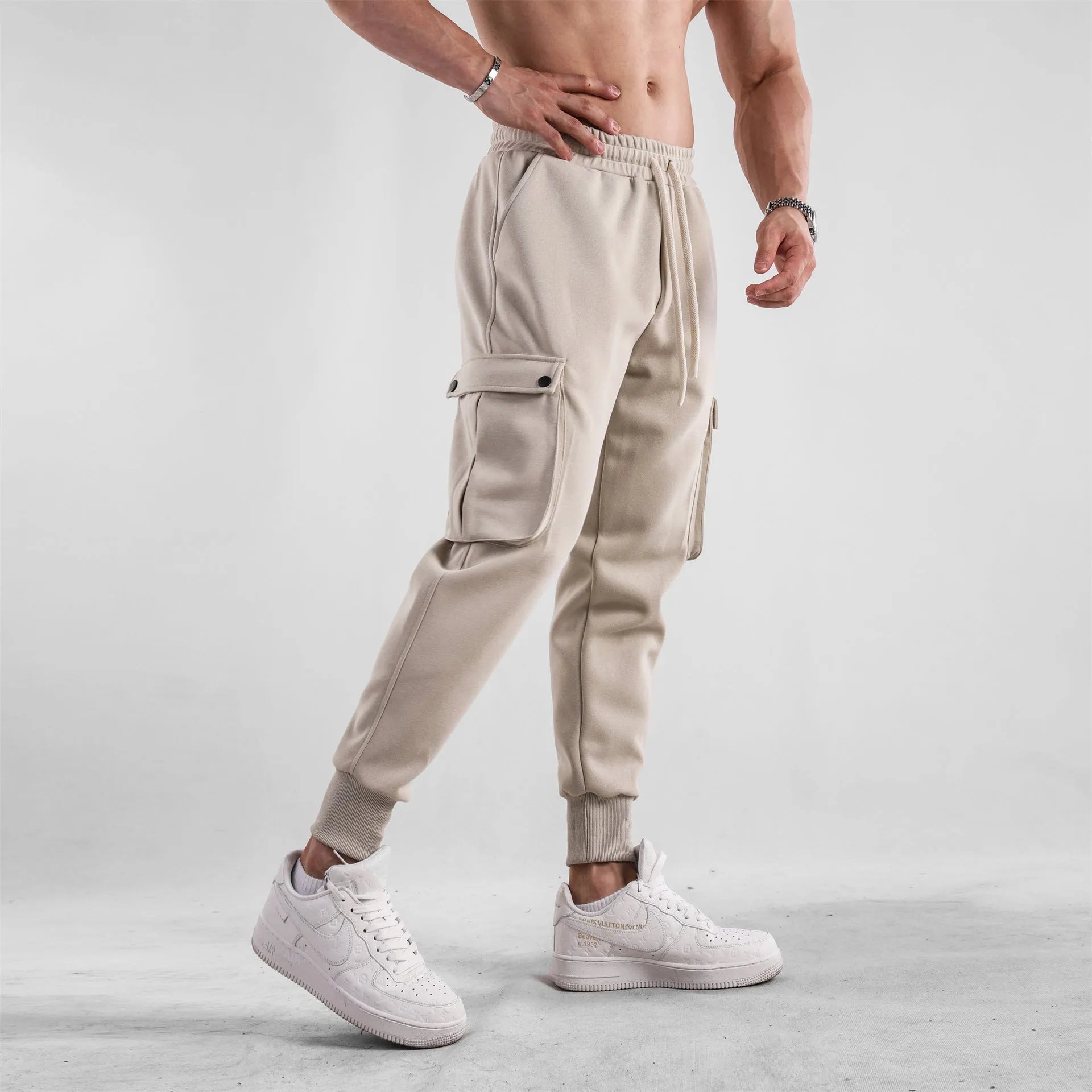 Men's loose-fit cotton sports trousers with ankle-tied cuffs and multiple pockets in a light grey colour.