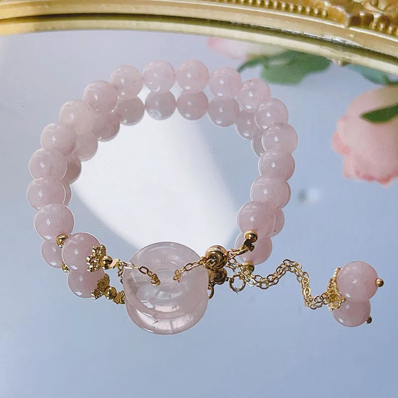 Pink crystal peace buckle bracelet on a metallic chain for women.