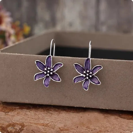 A pair of retro-style purple flower-shaped alloy earrings for women on a plain background.