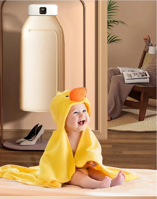 White cylindrical foldable clothes drier with remote control on a table.