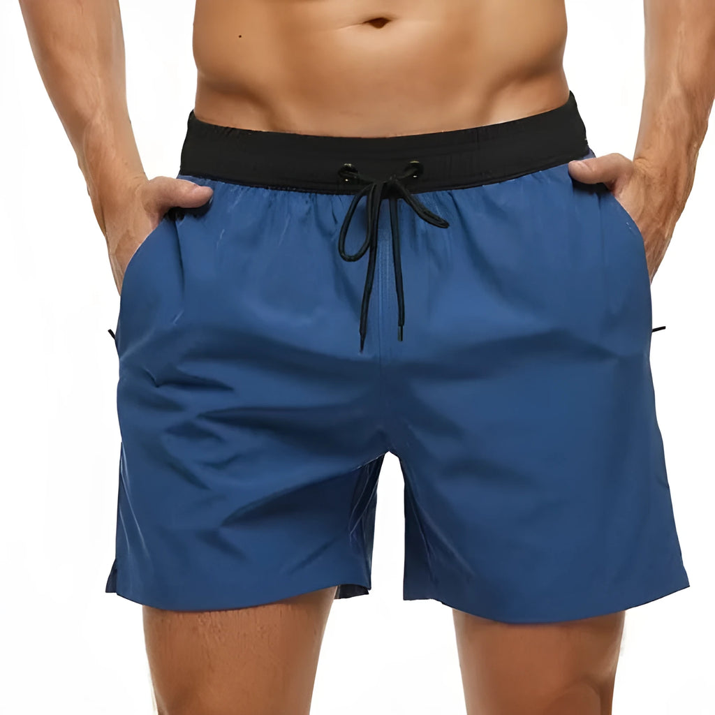Men's blue drawstring fitness shorts with a zippered side pocket and stitching detail on the waistband.
