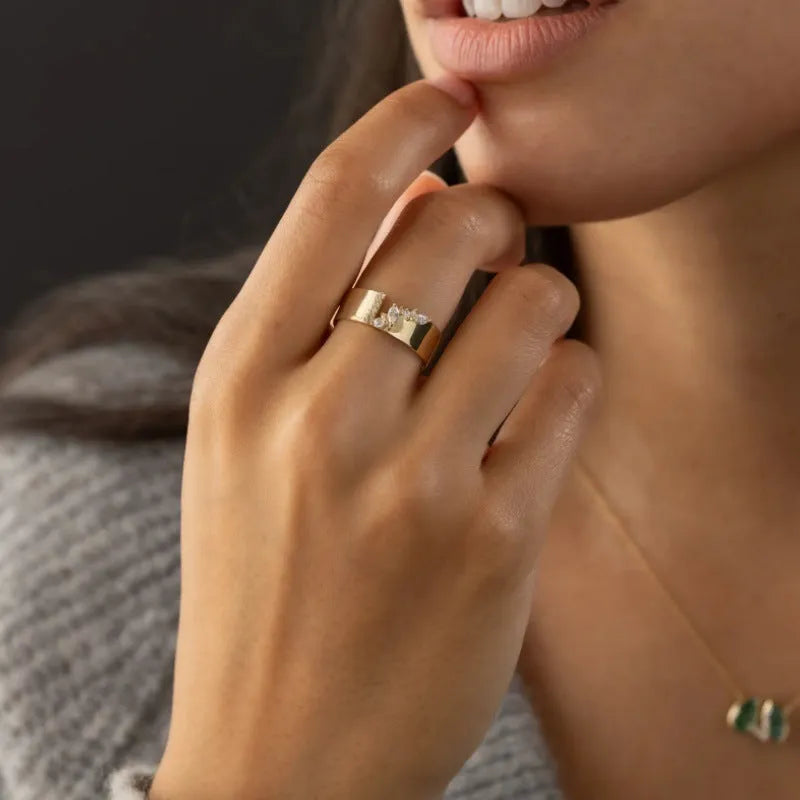 Gold-coloured women's fashion ring with shining zircon stones on a metal band