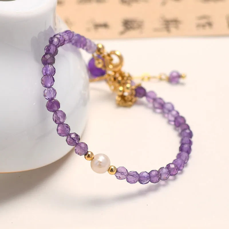 Close-up of a women's amethyst bracelet with diamond-cut crystal beads and Chinese style design.