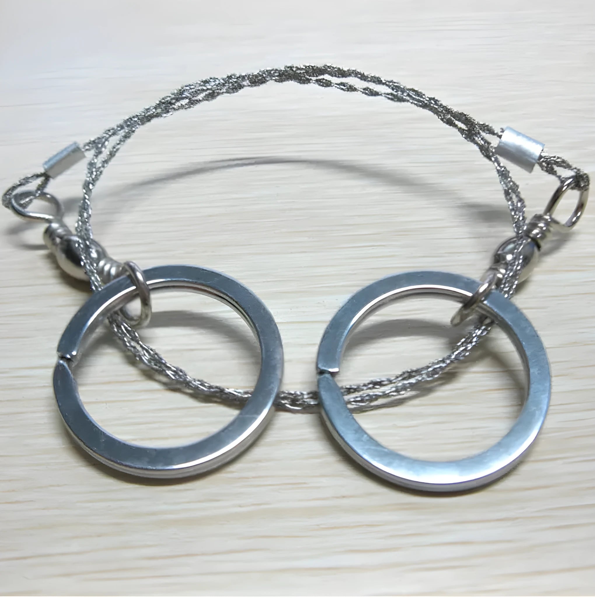 Stainless steel survival wire saw with pull rings, showing coiled 55 cm blade.