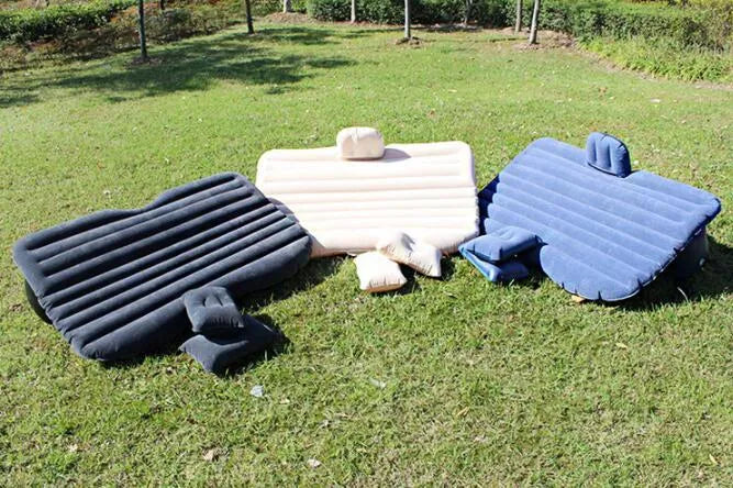 Black inflatable car bed with flocked material set up in the back of a five-seater vehicle, showing two pillows.