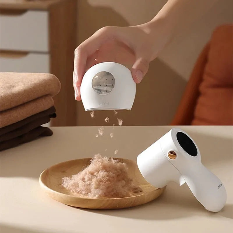 White electric lint remover with LED display and USB port on a fabric background.
