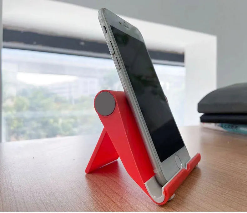 Black PE plastic folding stand holding a tablet at an adjustable angle on a wooden desk.