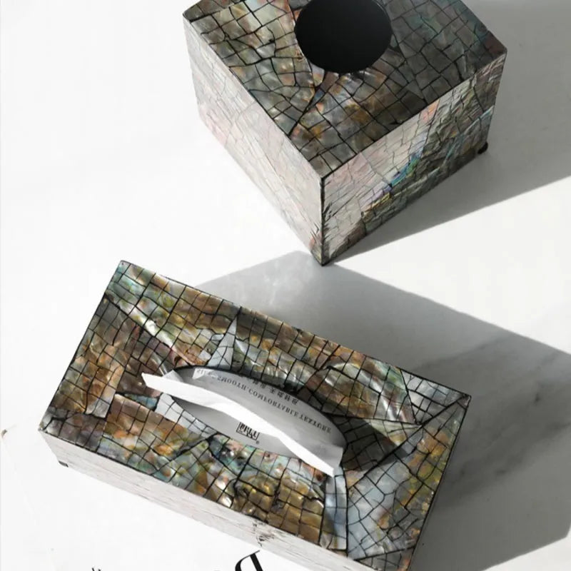A black rectangular shell tissue box holder with a removable lid on a wooden coffee table.