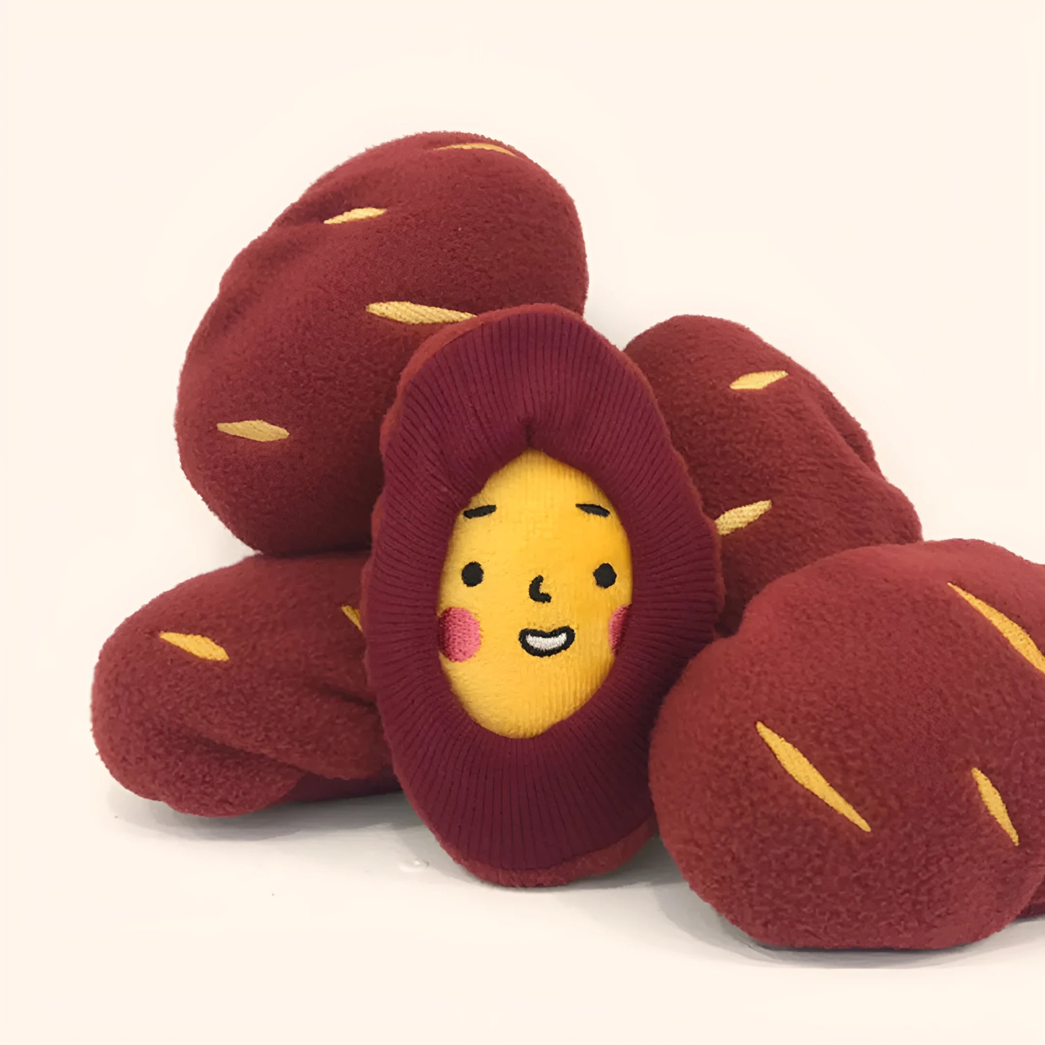 Red sweet potato-shaped dog toy with a peelable layer and hidden treat pocket for interactive play.