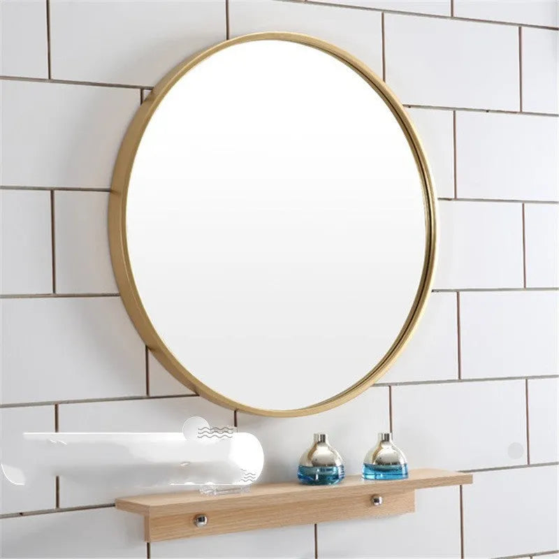 Round metal-framed wall mirror in black, white, or gold, shown in a bathroom setting.