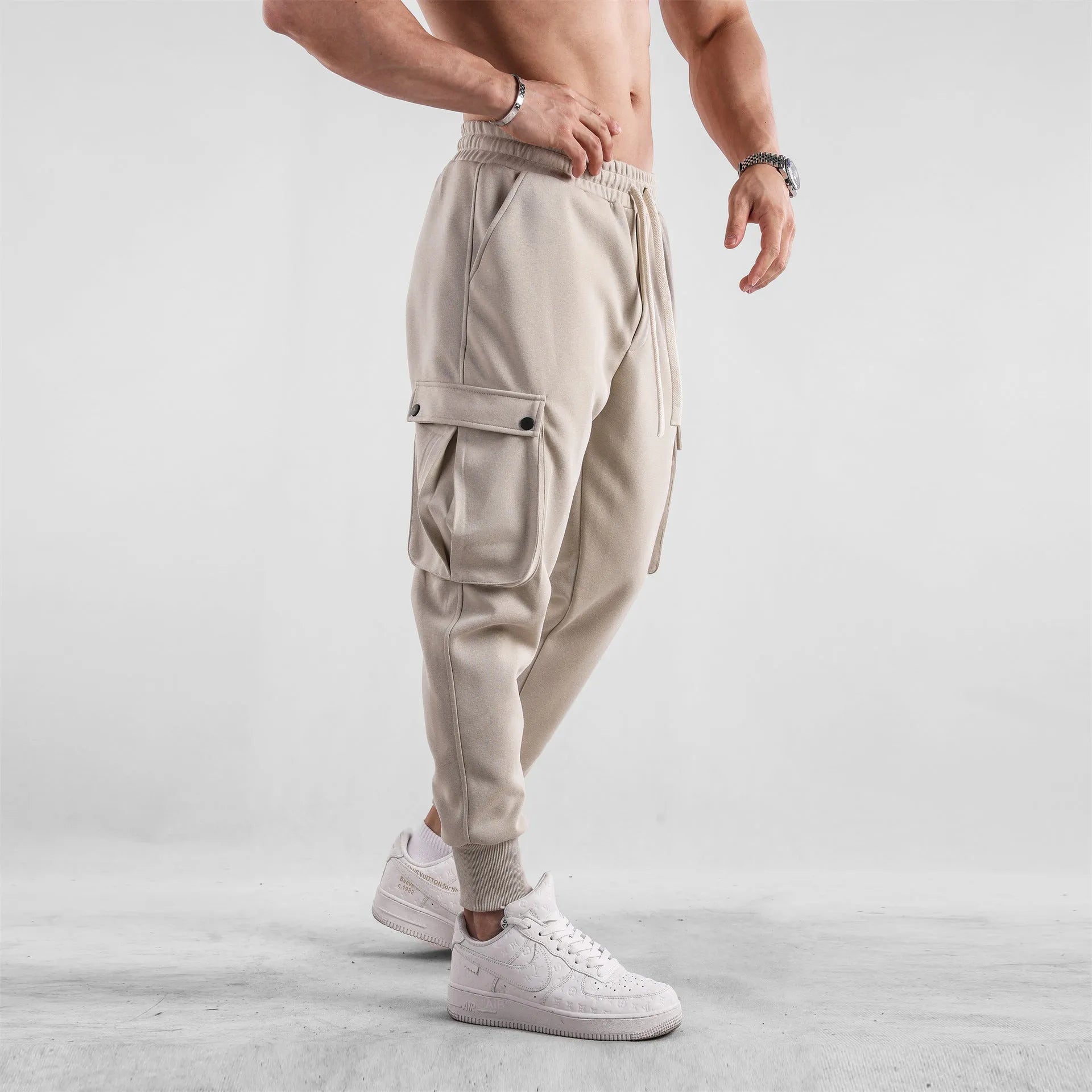 Men's loose-fit cotton sports trousers with ankle-tied cuffs and multiple pockets in a light grey colour.