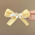 Yellow bow hair barrette with rhinestone pearl detailing and duckbill clip design