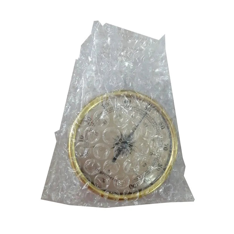 Analogue thermometer and hygrometer with aluminium ring and dial on a white wall.