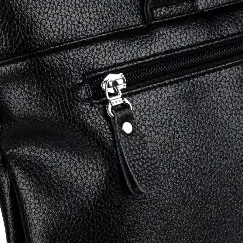 Men's black PU leather shoulder messenger bag with splicing detail on a table