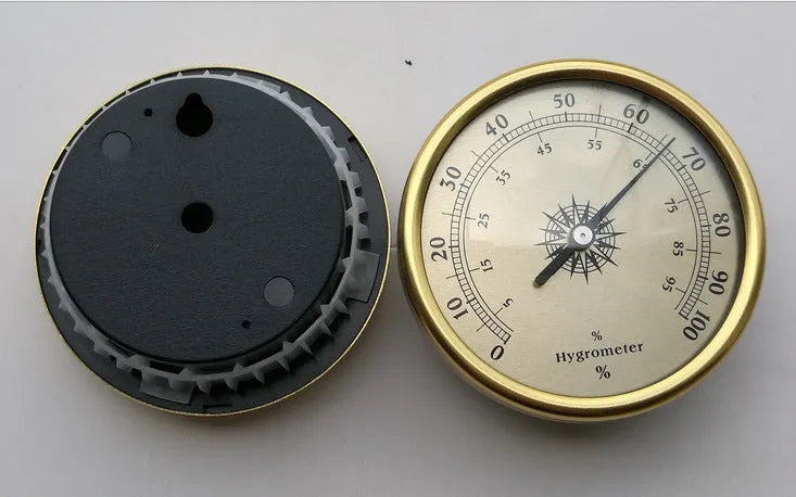 Analogue thermometer and hygrometer with aluminium ring and dial on a white wall.