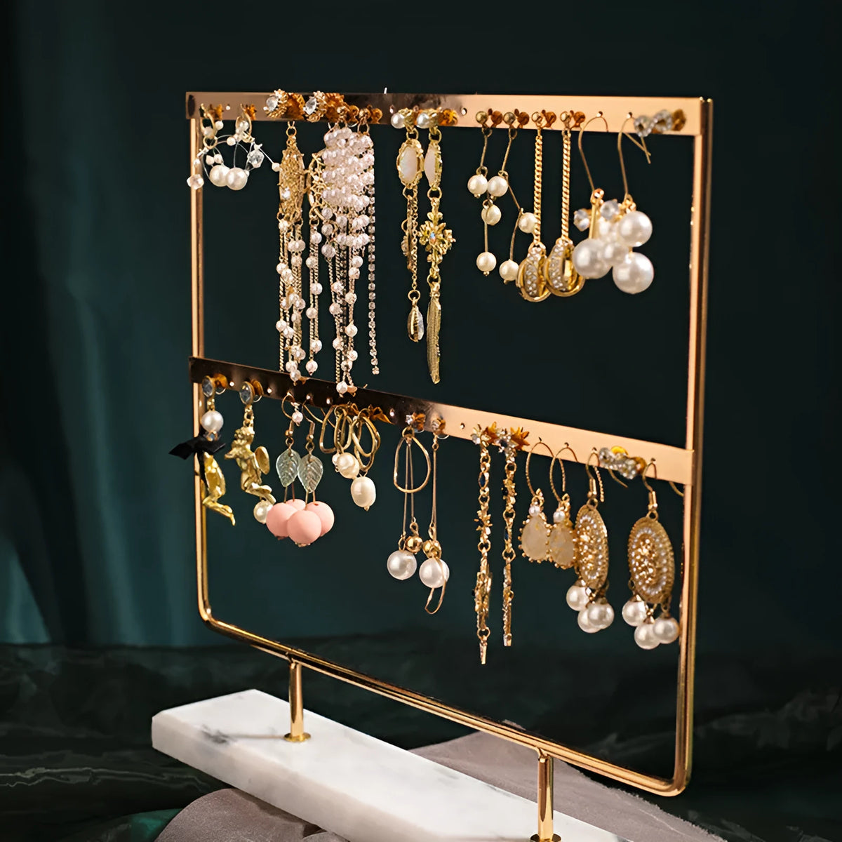 Alloy earring storage rack in green holding stud and drop earrings on a desktop