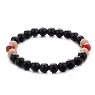 Natural stone beaded bracelet with a lava stone charm for essential oils on a wrist.