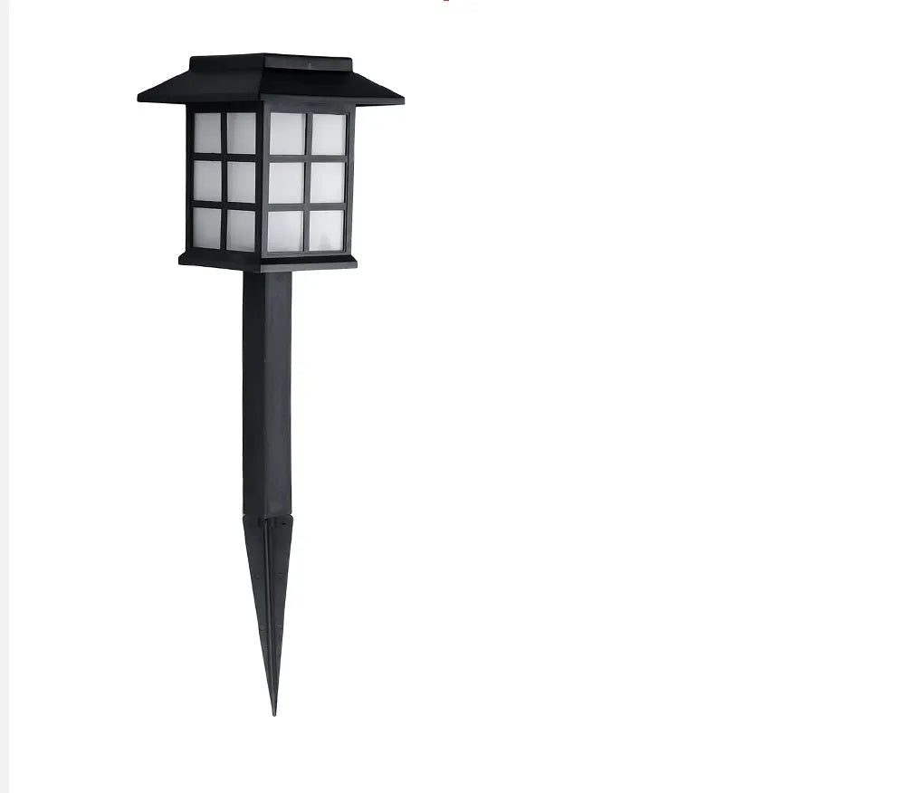 Black solar-powered outdoor LED lawn light with window-style openings, shown in a garden setting.