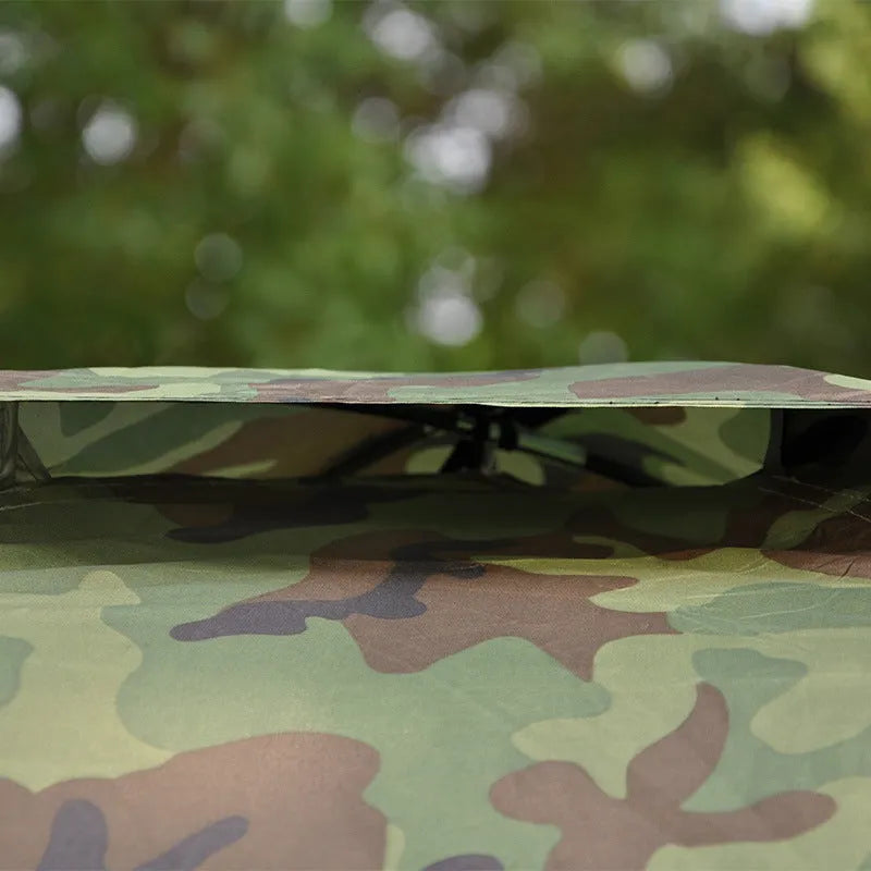 Green camouflage two-person camping tent with fibre glass poles and steel pegs pitched outdoors.