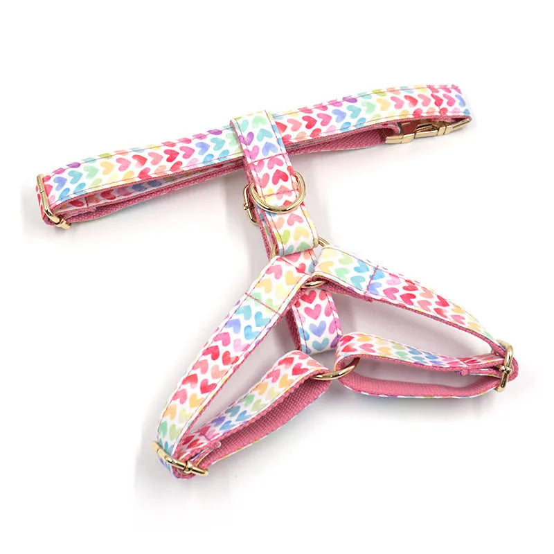 Pink colourful dog harness with gold buckle and heart-shaped stones on chest and back strap.