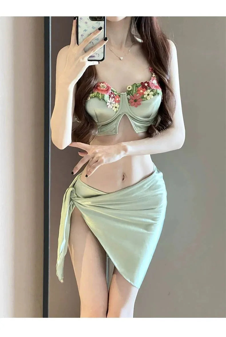 Green women's three-piece bikini set showing triangle top, briefs, and removable skirt laid flat.