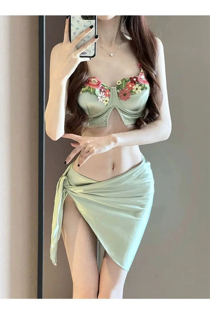 Green three-piece women's bikini set with triangle top, briefs, and coordinating skirt on mannequin