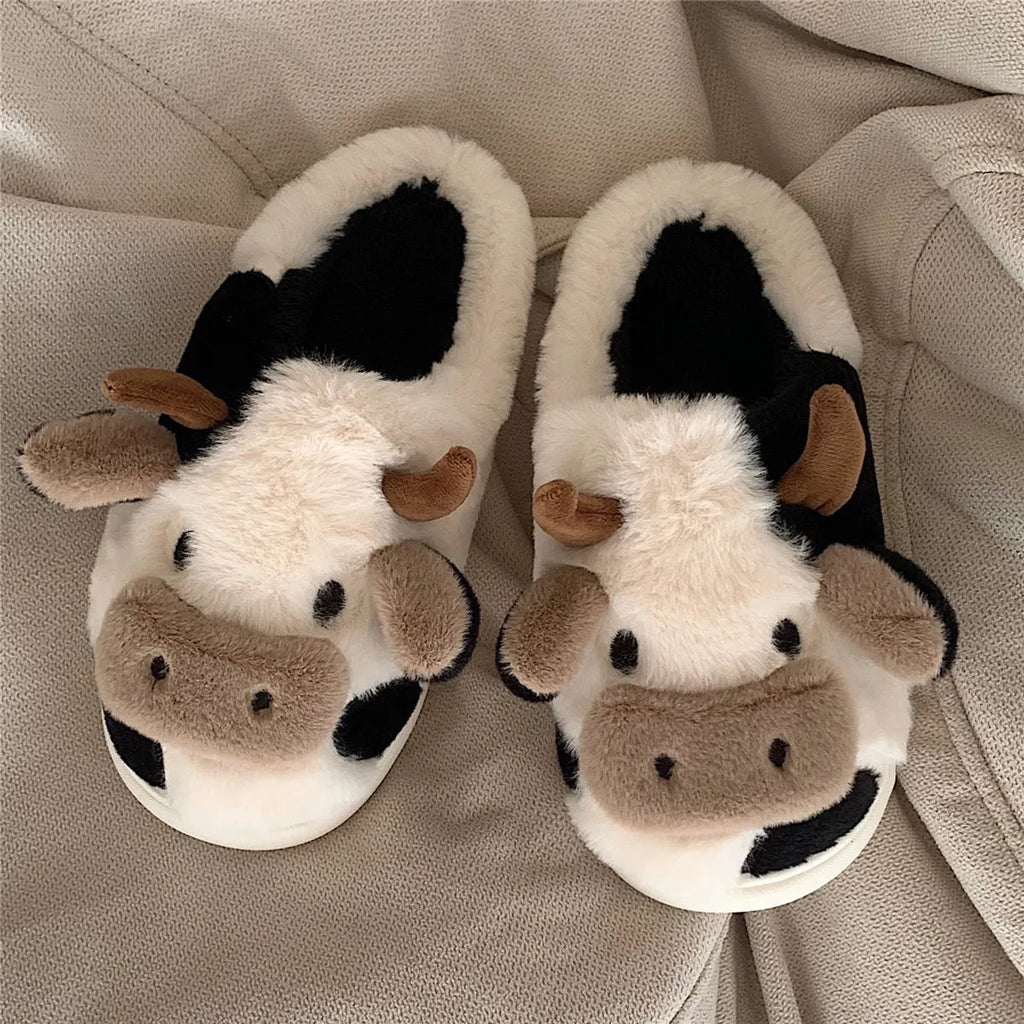 White cow-themed faux fur slippers with black spots and a textured grey anti-slip sole.