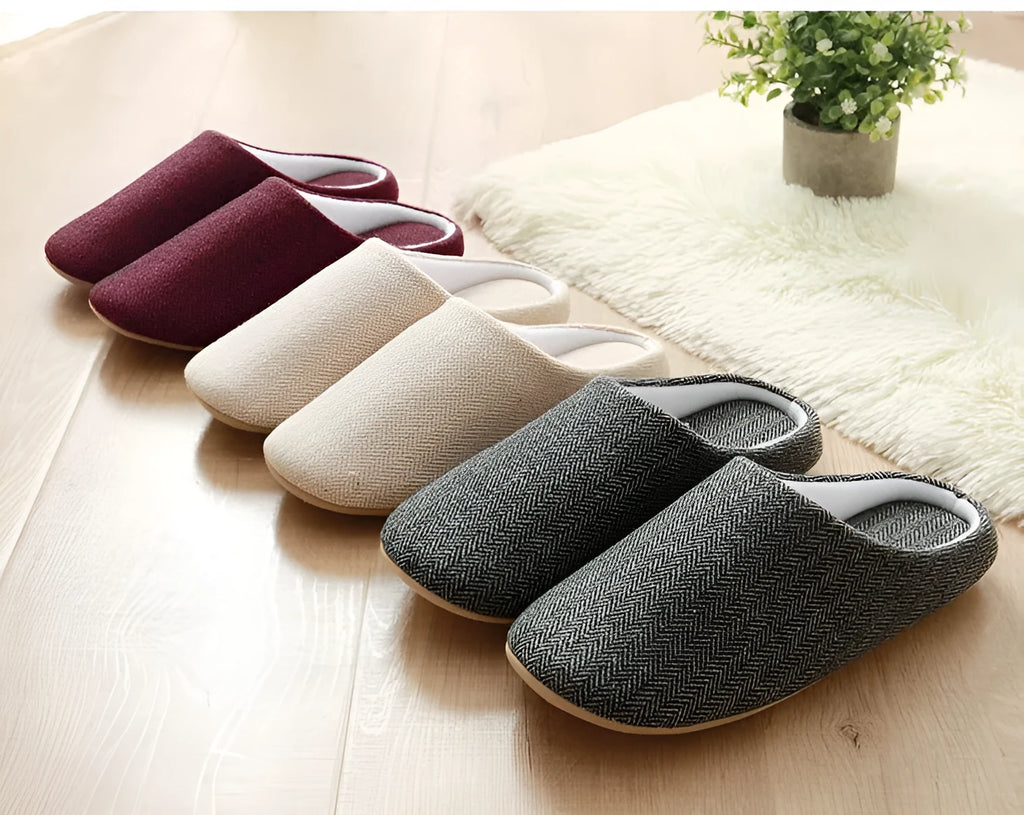 Men's black cotton indoor slippers with soft anti-skid sole on a wooden floor