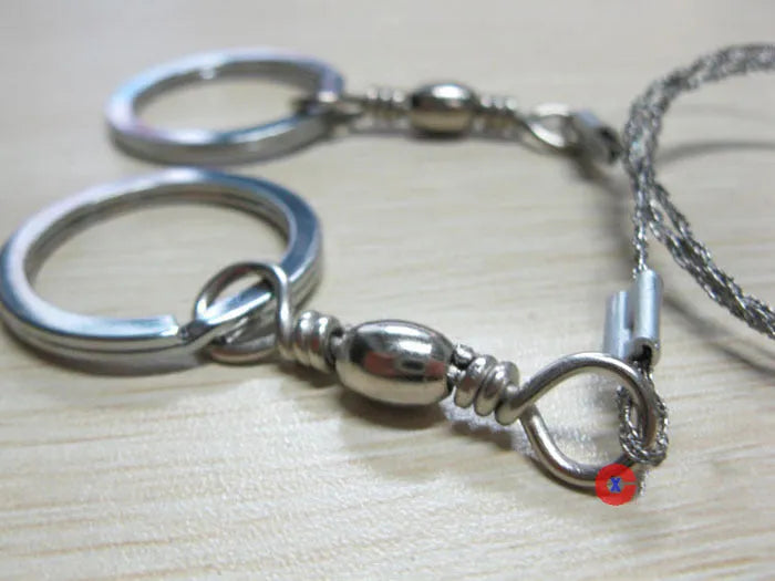 Stainless steel survival wire saw with pull rings, showing coiled 55 cm blade.