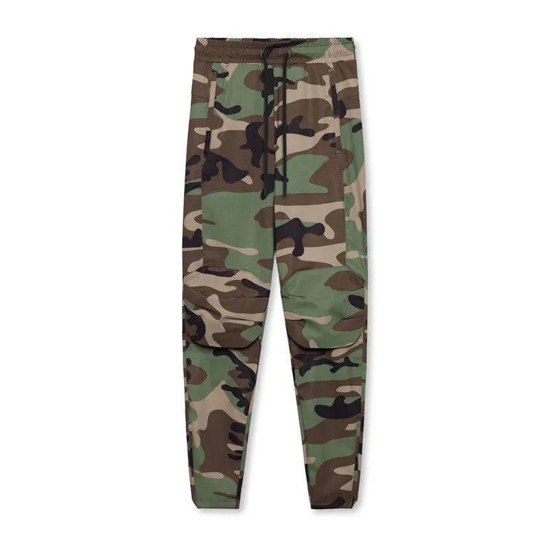 Men's loose grey fitness trousers with elasticated ankle ties on a gym floor.
