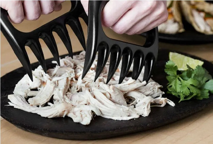 Two black bear claw meat shredding forks for barbecue and kitchen use on a kitchen counter.