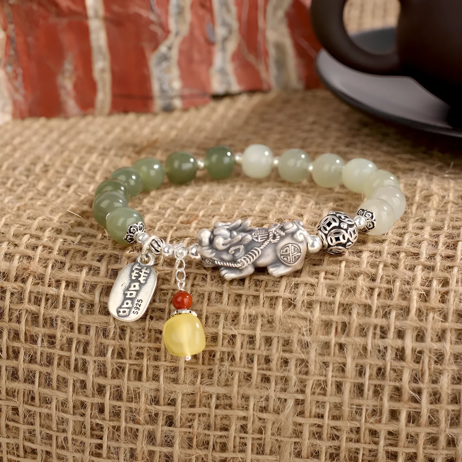 Close-up of a retro women's bracelet with a natural Hetian jade bead and a silver coin pendant on a wrist.