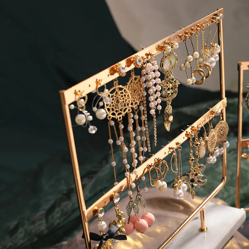 Alloy earring storage rack in green holding stud and drop earrings on a desktop