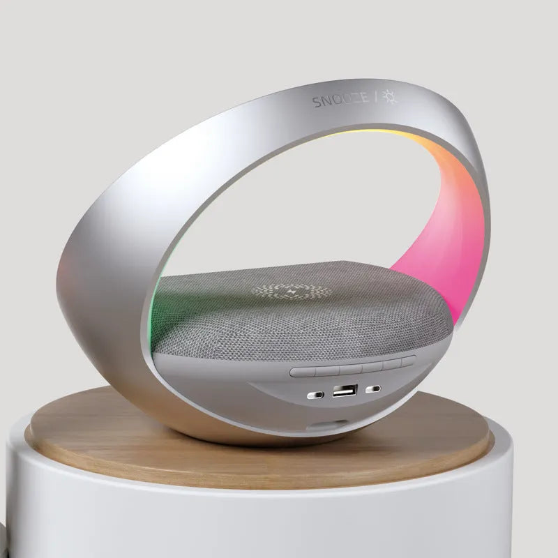 Beige or grey multifunctional desk unit with wireless charging pad, speaker grille, digital clock display, and LED light panel