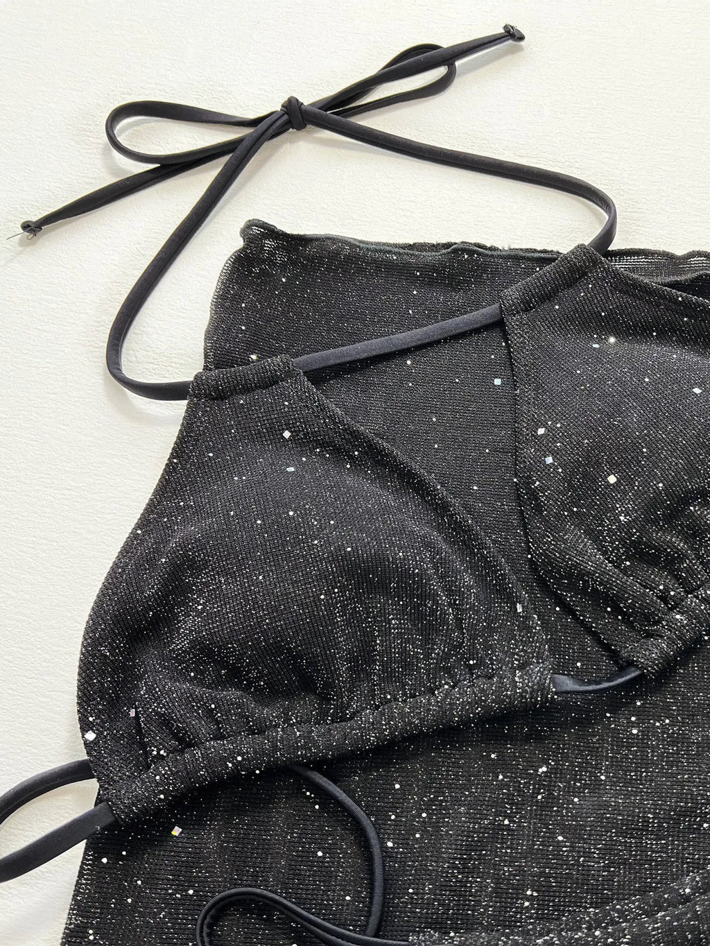 Black three-piece bikini swimsuit set with top and shorts on a mannequin.
