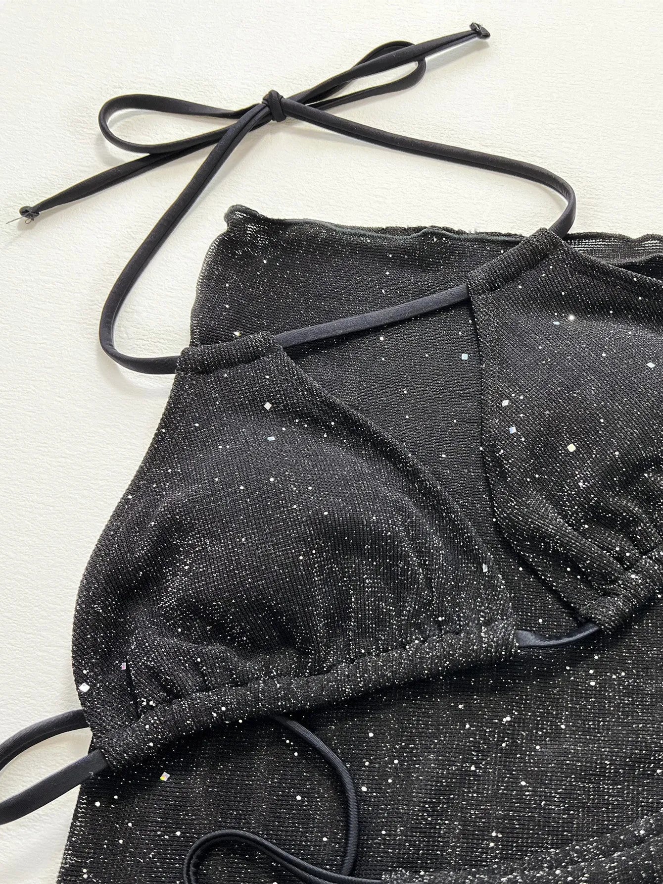 Black three-piece bikini swimsuit set with top and shorts on a mannequin.