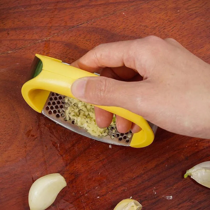 Stainless steel garlic press with curved ergonomic design and non-slip handle in assorted colours.