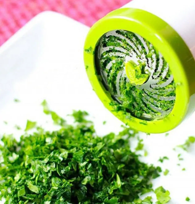 White and silver handheld herb grinder with removable top on a kitchen counter.