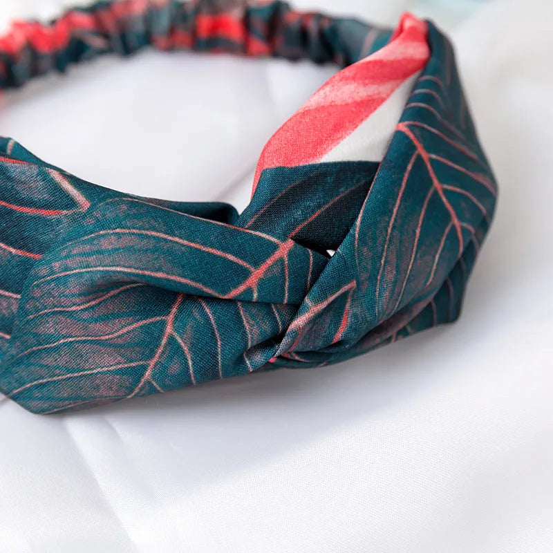 Red cloth headband for women with a banana leaf and cross pattern, showing elastic band.