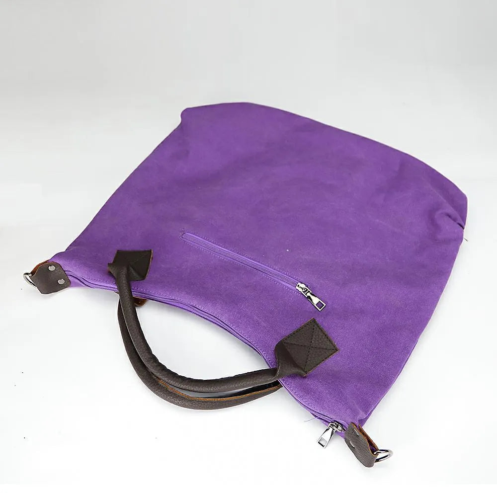 Women's canvas handbag in lake blue with zipper closure, hard handle, and double strap roots for shoulder or crossbody carry