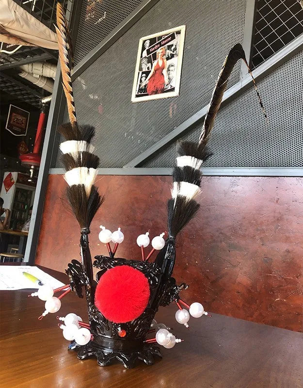 Black crown ornament with a long feather for decorating a motorcycle helmet.