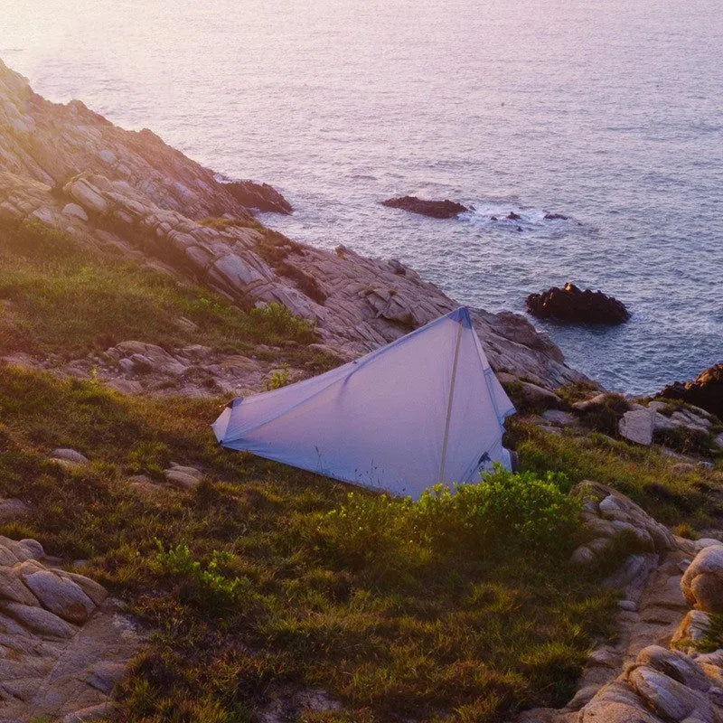 Silicon coated outdoor camping pyramid tent in green pitched on grass showing fly and aluminium pole