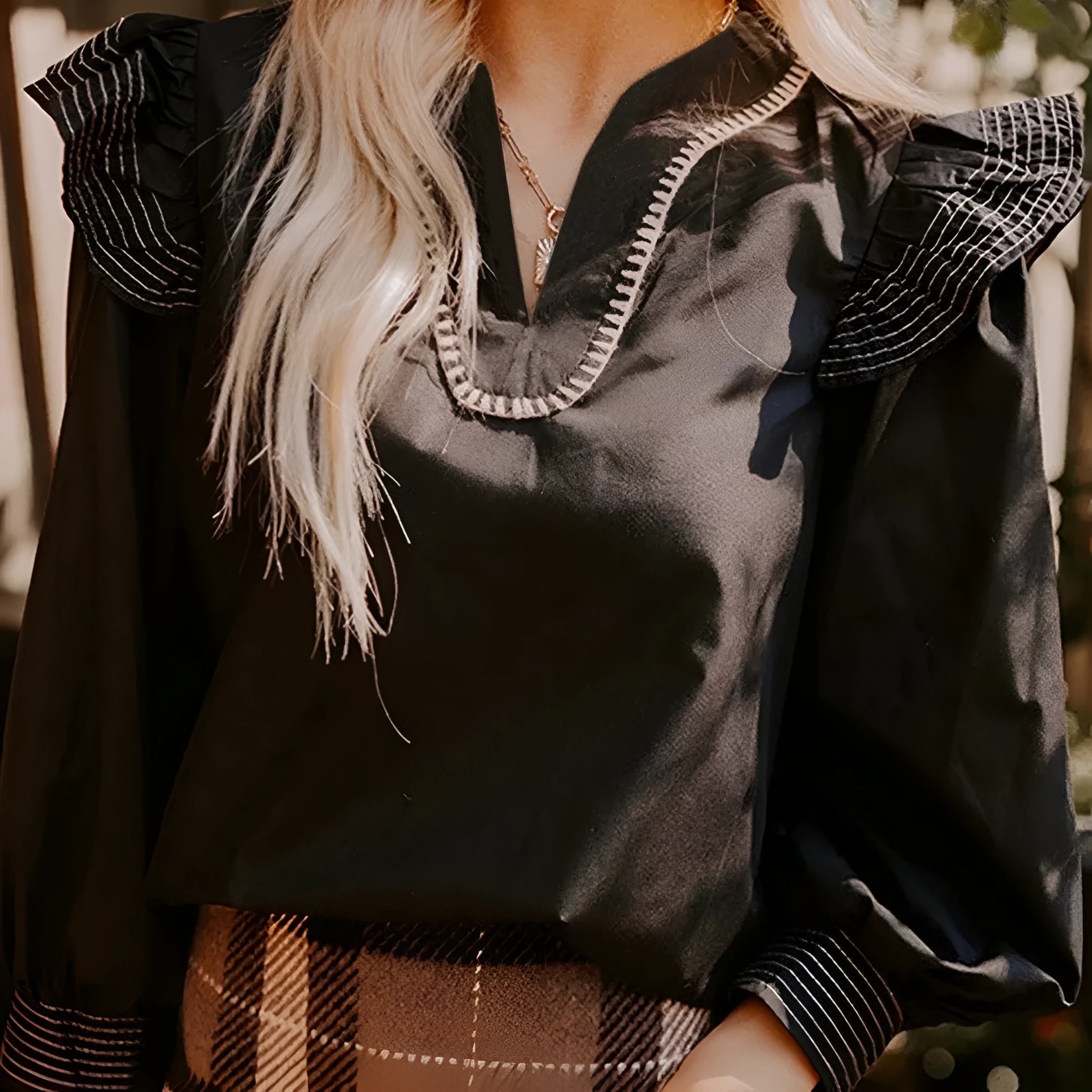 Black women's V-neck blouse with ruffled long sleeves and contrast stitching.