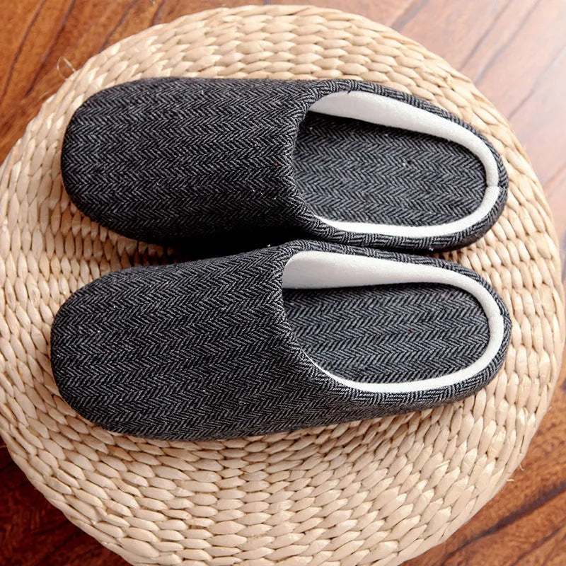 Men's black cotton indoor slippers with soft anti-skid sole on a wooden floor