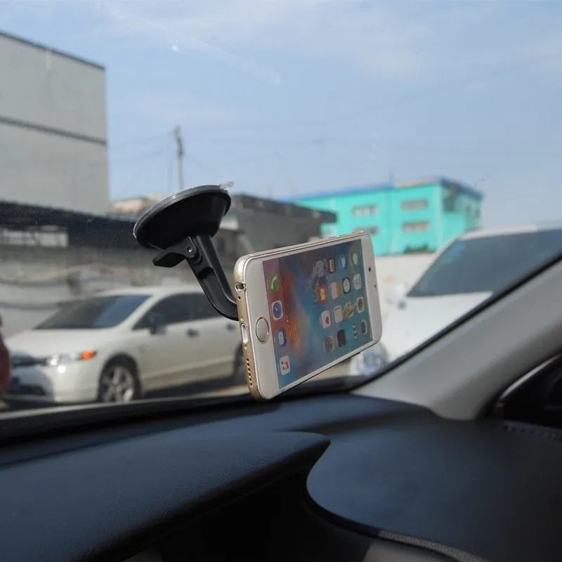 Black magnetic car phone holder mounted on dashboard with phone attached, showing 360-degree rotation capability