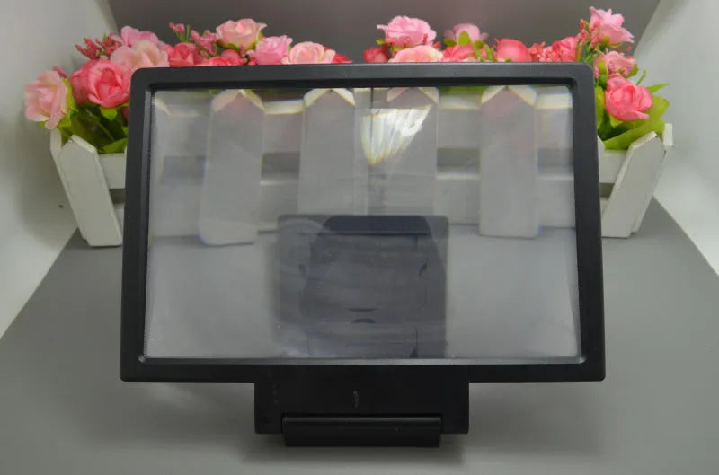 Black and white foldable screen amplifier lens for mobile phones, shown next to a smartphone for scale.