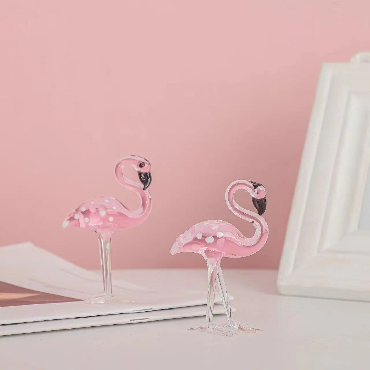 A pink flamingo decorative ornament made from clear white crystal on a table.