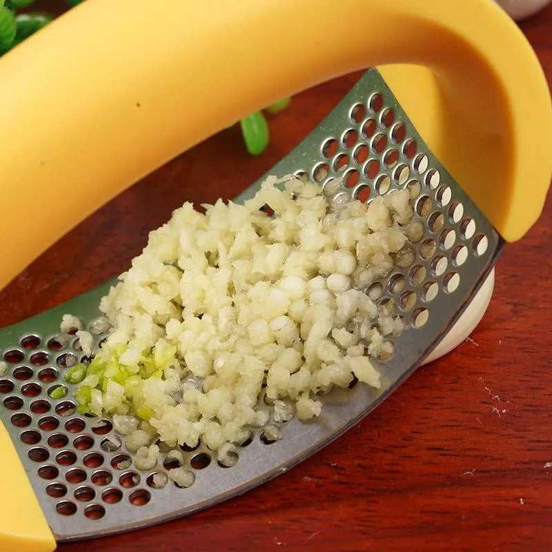 Stainless steel garlic press with curved ergonomic design and non-slip handle in assorted colours.